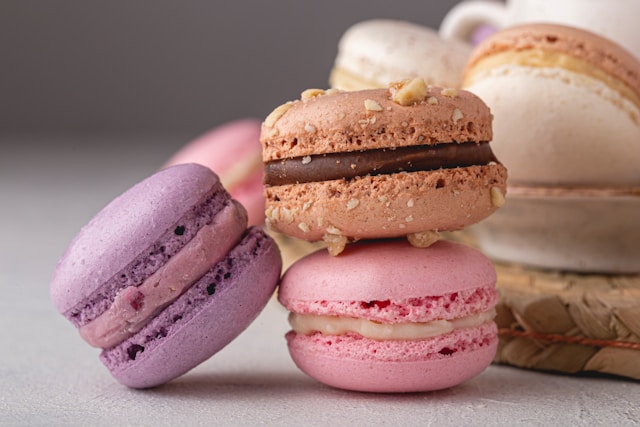 Närbild av en färgstark macaron med mjuk bakgrund som för tankarna till ett hemtrevligt bageri